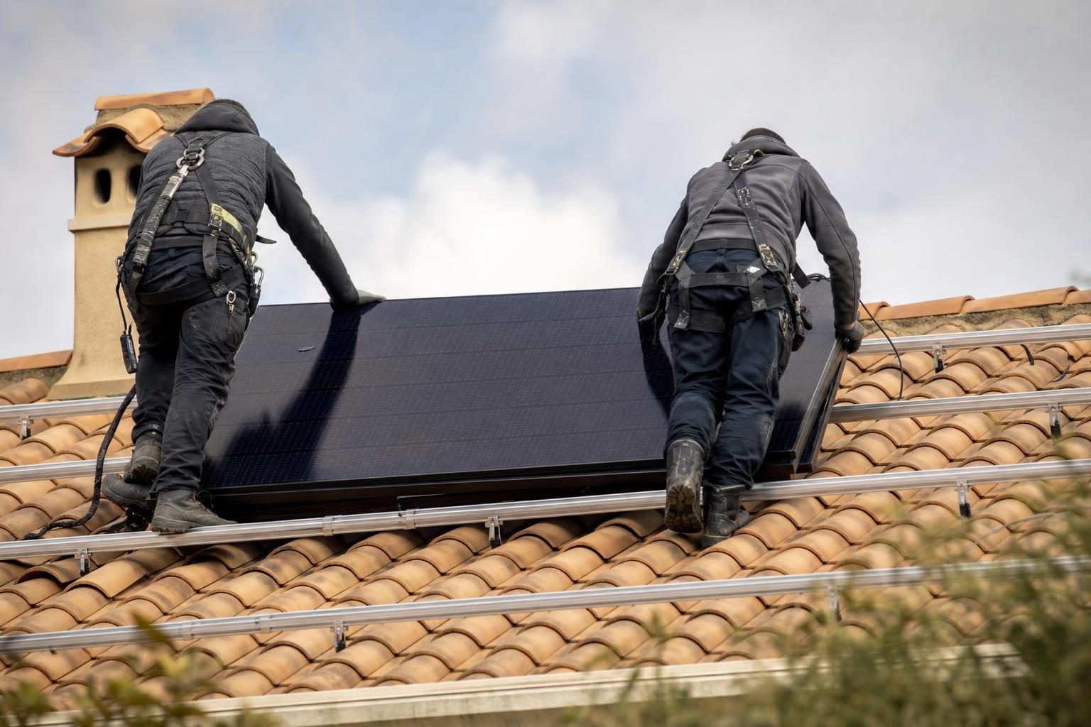 Pose de panneaux solaires sur un toit de tuiles (illustration)
